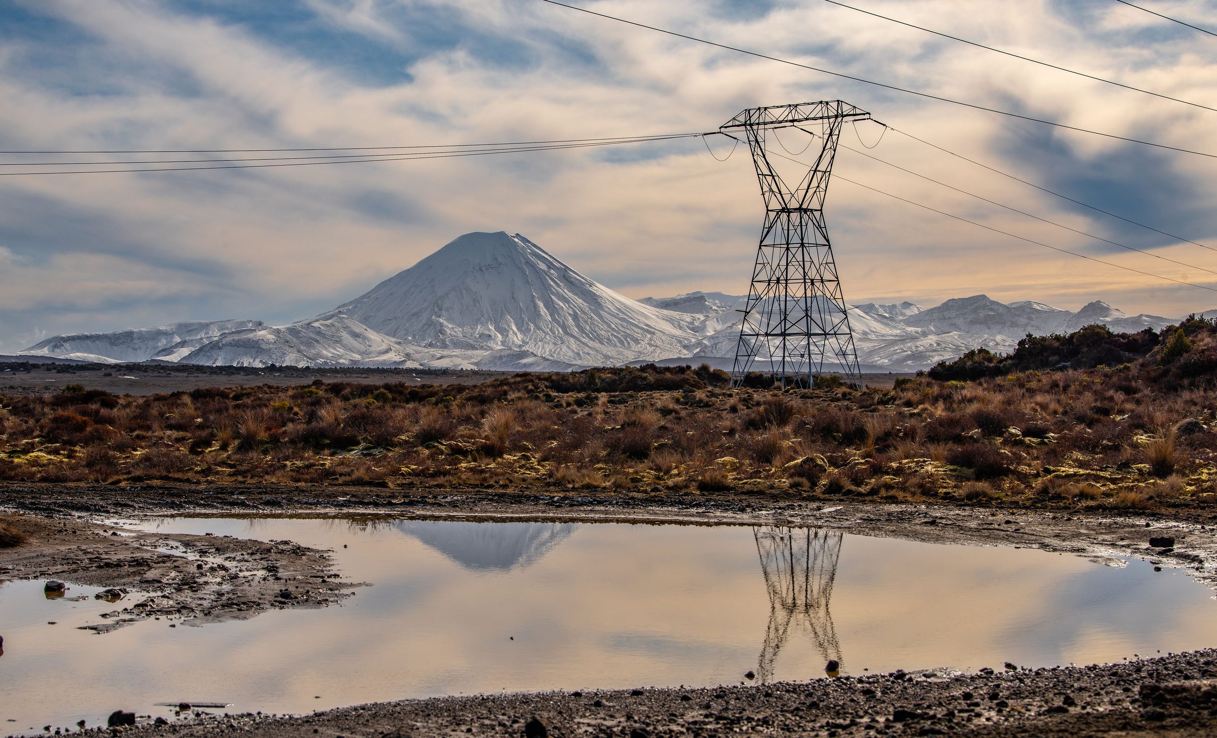 Transmission tower on the plateau beneath the snow-capped peak of Mount Ngauruhoe